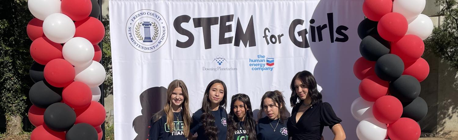 STEM for girls posing in front of banner